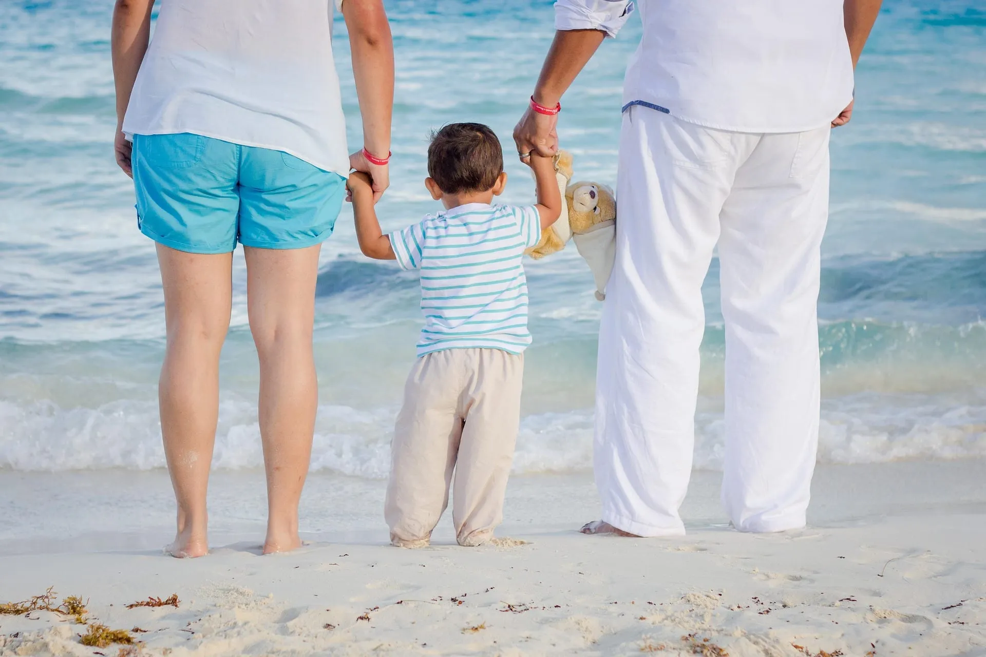 A family holding hands walking into the ocean at the beach