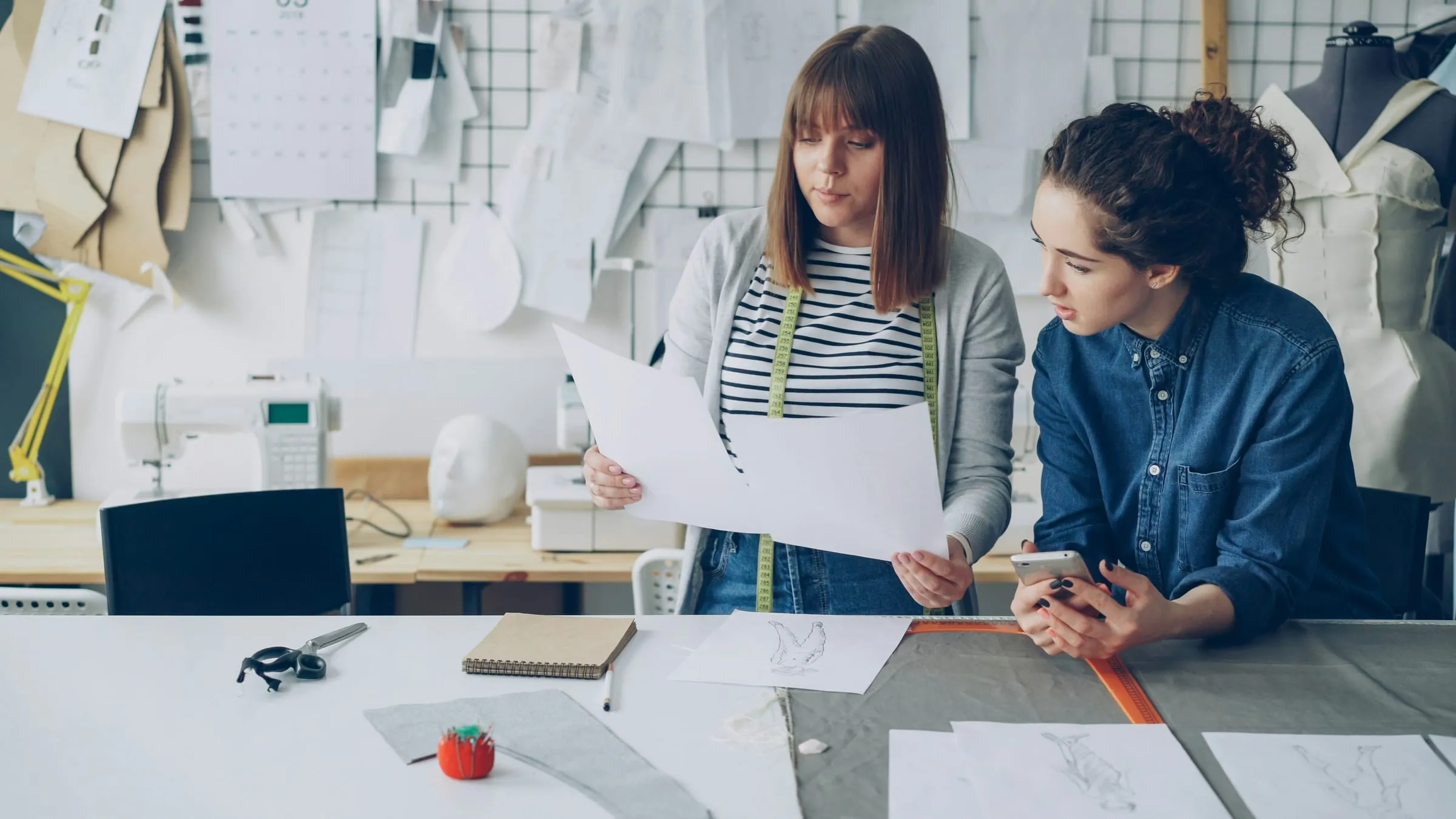 Two designers working with fabric and patterns in a tailoring studio